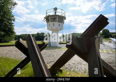 17 giugno 2023, Thürigen, Mödlareuth: Una torre di guardia e impianti di sicurezza di frontiera sull'ex confine interno tedesco vicino a Mödlareuth. A causa della sua somiglianza con il muro di Berlino, la sezione di confine divenne nota anche come "piccola Berlino". Oggi, il memoriale del Museo tedesco-tedesco si trova qui. Foto: Heiko Rebsch/dpa Foto Stock