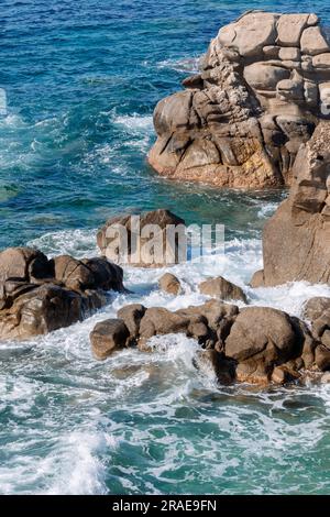 Onde sulla spiaggia rocciosa, riva del mare con onde che si infrangono sulle grandi rocce Foto Stock