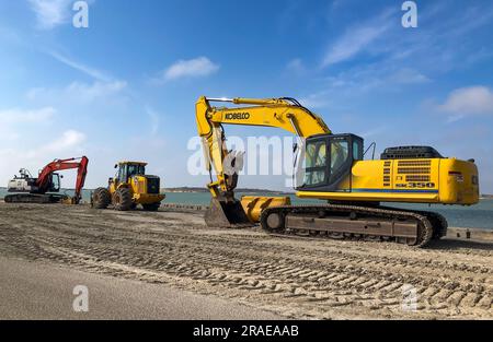 PORT ARANSAS, TX - 28 FEB 2023: Escavatore giallo Kobelco e altri macchinari pesanti per la costruzione su sabbia vicino all'acqua in una giornata soleggiata con cielo prevalentemente blu. Foto Stock