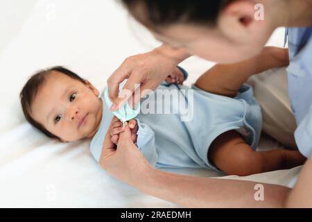 la madre taglia le unghie delle mani del neonato con le forbici per unghie. Foto Stock