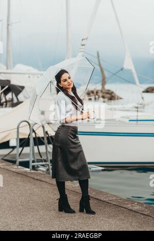 Ritratto all'aperto di una giovane donna sotto la pioggia, con ombrello, immagine in stile moda Foto Stock