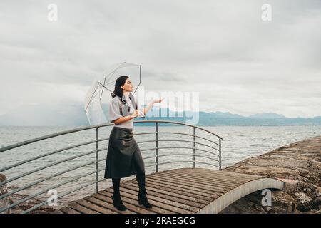 Ritratto all'aperto di una giovane donna sotto la pioggia, con ombrello, immagine in stile moda Foto Stock