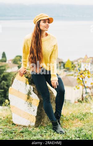 Ritratto all'aperto di una bella giovane donna, che indossa un caldo pullover giallo lavorato a maglia e un cappello Foto Stock