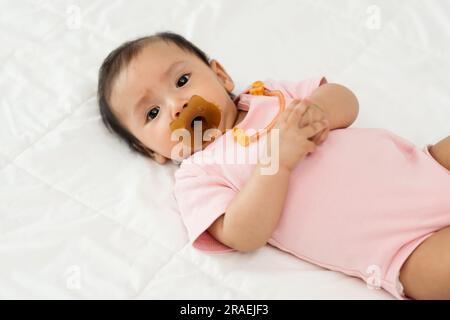 la neonata succhia con il succhietto su un letto Foto Stock