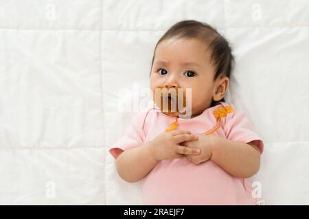 la neonata succhia con il succhietto su un letto Foto Stock