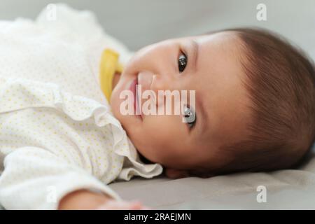 un bambino felice che sorride mentre è sdraiato su un letto Foto Stock