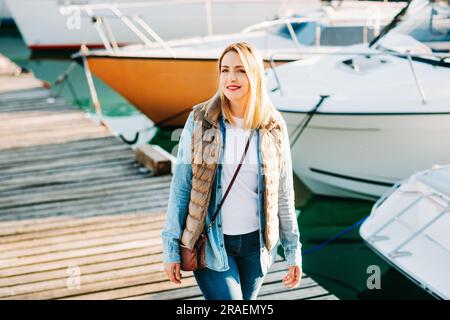 Ritratto di moda all'aperto di una bella giovane donna che posa vicino al lago in un piccolo porto Foto Stock