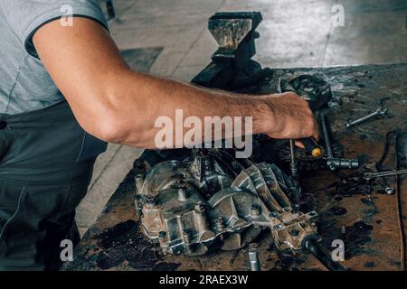 Riparazione meccanica cambio su banco di lavoro in metallo in officina. Meccanico automatico al lavoro. Flusso di lavoro autentico. Mani da vicino. Foto Stock