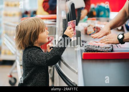 Bambino che acquista frutta in un negozio di alimentari, con un conto di 20 chf Foto Stock