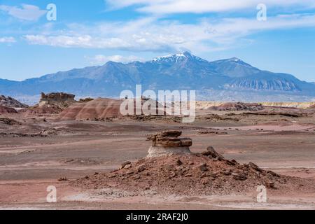 Un caprock di arenaria su un hoodoo di argilla nelle colline bentonite del deserto di Caineville vicino a Hanksville, Utah, con le Henry Mountains alle spalle. Foto Stock