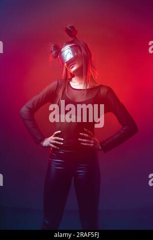 Ritratto di una bella donna cyber model che indossa occhiali futuristici sulla testa con luce al neon in un ambiente tecnologico virtuale Foto Stock