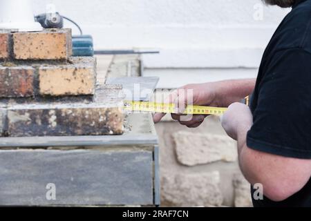 L'installatore le misure e le mette segni per il taglio e la posa di un tile Foto Stock