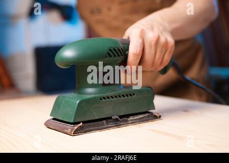 Primo piano delle tavole di legno levigatrici per falegname con levigatrice elettrica Foto Stock