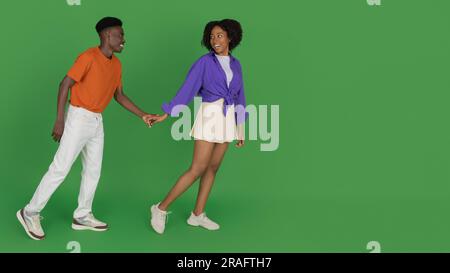 Una giovane donna afroamericana sorridente in una mano da fidanzato, conduce Foto Stock