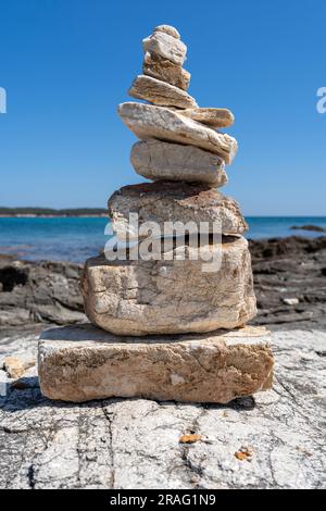 Pietre impilate su una spiaggia rocciosa nel Mar Egeo Foto Stock