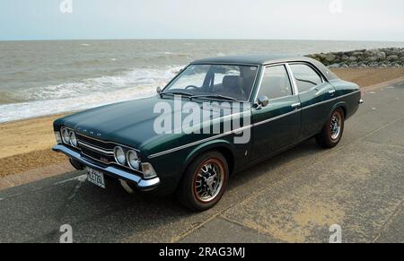 La classica Ford Cortina Mark 3 è parcheggiata sul lungomare, sulla spiaggia e sul mare sullo sfondo. Foto Stock