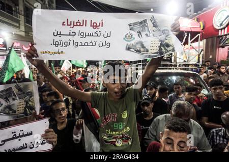 3 luglio 2023, Gaza City, Striscia di Gaza, Palestina: I sostenitori di Hamas sventolano bandiere islamiche verdi mentre alzano le mani e cantano slogan durante una protesta contro un raid militare israeliano nella città di Jenin in Cisgiordania, sulla strada principale del campo profughi di Jebaliya, nella parte settentrionale della Striscia di Gaza, lunedì 3 luglio 2023. Israele ha colpito bersagli in una roccaforte militante nella Cisgiordania occupata con droni all'inizio di lunedì e ha schierato centinaia di truppe nella zona. Funzionari sanitari palestinesi hanno detto che almeno otto palestinesi sono stati uccisi. (Immagine di credito: © Mahmoud Issa/Quds Net News via ZUMA Press Wire) EDITORIALE Foto Stock