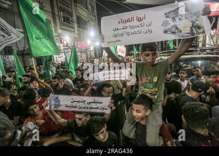 3 luglio 2023, Gaza City, Striscia di Gaza, Palestina: I sostenitori di Hamas sventolano bandiere islamiche verdi mentre alzano le mani e cantano slogan durante una protesta contro un raid militare israeliano nella città di Jenin in Cisgiordania, sulla strada principale del campo profughi di Jebaliya, nella parte settentrionale della Striscia di Gaza, lunedì 3 luglio 2023. Israele ha colpito bersagli in una roccaforte militante nella Cisgiordania occupata con droni all'inizio di lunedì e ha schierato centinaia di truppe nella zona. Funzionari sanitari palestinesi hanno detto che almeno otto palestinesi sono stati uccisi. (Immagine di credito: © Mahmoud Issa/Quds Net News via ZUMA Press Wire) EDITORIALE Foto Stock