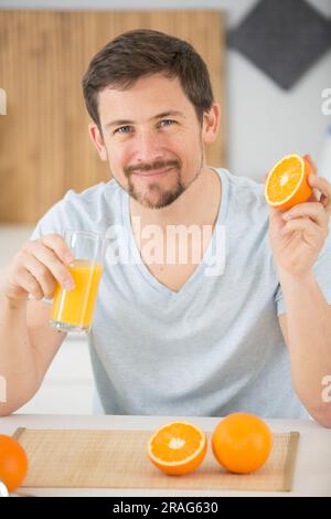 uomo che tiene arance fresche e un bicchiere di succo Foto Stock