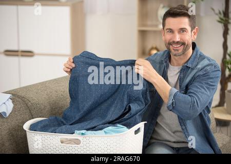 un uomo seduto sul divano che piegava il lavaggio Foto Stock