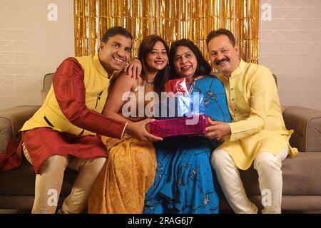 Felice famiglia indiana che si gode la stagione delle feste a Diwali. Regalarsi regali e godersi la vita e le feste con la famiglia Foto Stock