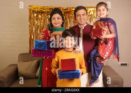 Felice famiglia indiana che si gode la stagione delle feste a Diwali. Regalarsi regali e godersi la vita e le feste con la famiglia Foto Stock