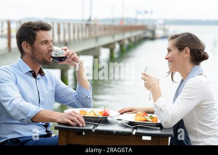 una coppia in vacanza estiva beve vino al ristorante sul mare Foto Stock