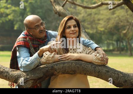 Una coppia indiana anziana si diverte a trascorrere una bella serata romantica nel parco verde. Stanno godendo, sorridendo e trascorrendo momenti di gioia. Foto Stock
