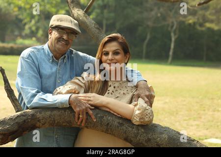 Una coppia indiana anziana si diverte a trascorrere una bella serata romantica nel parco verde. Stanno godendo, sorridendo e trascorrendo momenti di gioia. Foto Stock