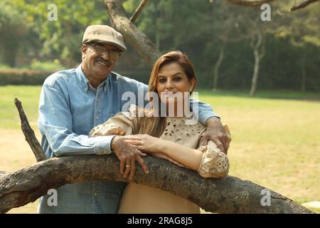 Una coppia indiana anziana si diverte a trascorrere una bella serata romantica nel parco verde. Stanno godendo, sorridendo e trascorrendo momenti di gioia. Foto Stock