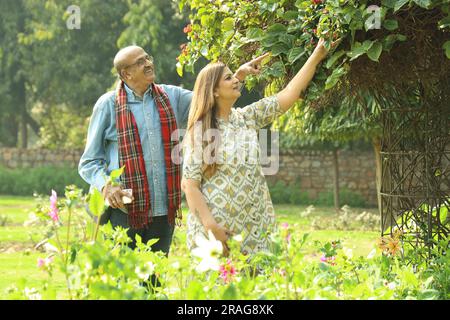 Una coppia indiana anziana si diverte a trascorrere una bella serata romantica nel parco verde. Stanno godendo, sorridendo e trascorrendo momenti di gioia. Foto Stock