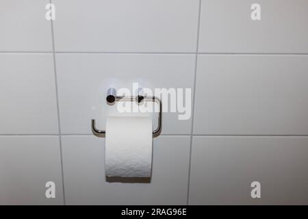 Vista ravvicinata del supporto a parete per carta igienica su parete bianca isolata del bagno. Foto Stock