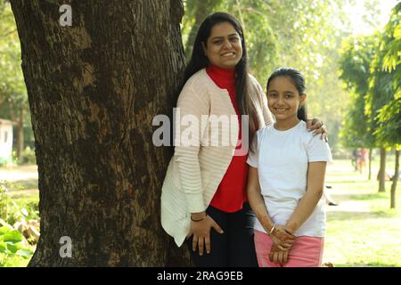 Madre e figlia indiane che si divertono insieme nel parco di giorno. La figlia è amata e si sente al sicuro con sua madre. Foto Stock