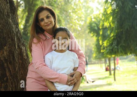 Madre e figlia indiane che si divertono insieme nel parco di giorno. La figlia è amata e si sente al sicuro con sua madre. Foto Stock