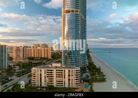 Alti hotel e condomini costosi sul fronte spiaggia sabbiosa sulla costa dell'oceano Atlantico nella città di Sunny Isles Beach al tramonto. Infrastrutture turistiche americane Foto Stock