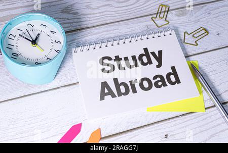 Il testo Study Abroad appare dietro carta marrone strappata Foto Stock