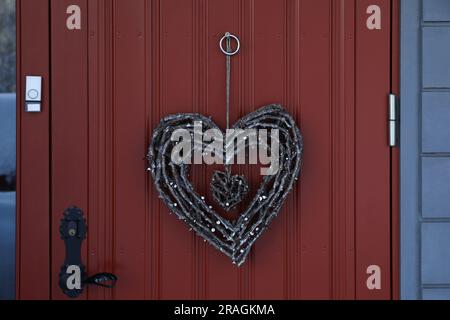 Splendida corona a forma di cuore fatta di ramoscelli appesi alla porta Foto Stock