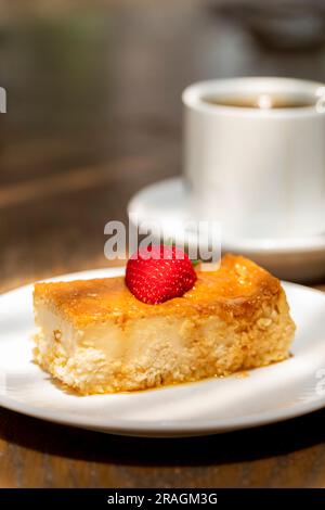 flan al caramello cotto in casa, con una fragola sulla parte superiore e caffè sul retro Foto Stock