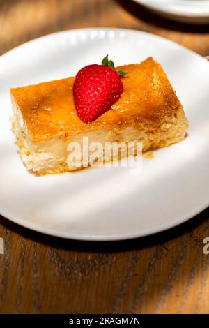 flan al caramello cotto in casa, con una fragola sulla parte superiore e caffè sul retro Foto Stock