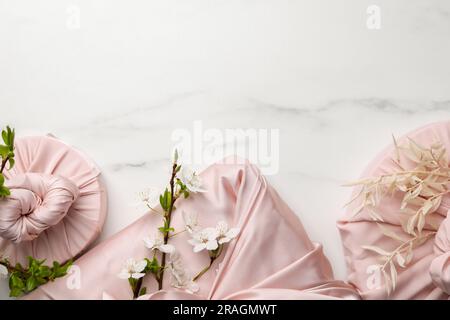 Tecnica Furoshiki. Regali confezionati in tessuto rosa su tavolo in marmo bianco, piatto. Spazio per il testo Foto Stock