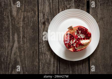 il melograno tagliato giace su un tavolo di legno da vicino Foto Stock