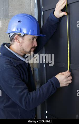 un costruttore sta misurando una porta Foto Stock