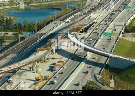 Lavori stradali per la costruzione di infrastrutture di trasporto americane. Ristrutturazione dello svincolo autostradale con traffico in movimento a Miami, Florida. Sviluppo Foto Stock