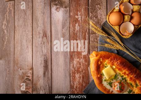 L'Adjarian Khachapuri è un tradizionale piatto georgiano di pane ripieno di formaggio sulguni con tuorlo d'uovo. Vista dall'alto. Copia spazio. Foto Stock