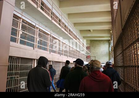 I turisti all'interno del penitenziario federale di Alcatraz che guardano i corridoi con celle carcerarie Alcatraz Island San Francisco California USA Foto Stock