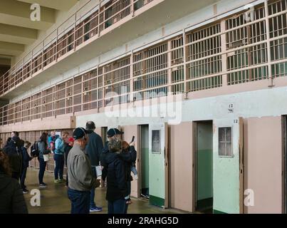 I turisti all'interno del penitenziario federale di Alcatraz che guardano i corridoi con celle carcerarie Alcatraz Island San Francisco California USA Foto Stock