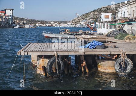 Vista sulla costa con vecchie attrezzature portuali. Baia di Balaklava, in una giornata di sole. È un insediamento nella penisola di Crimea e parte della città di Sebastopoli Foto Stock