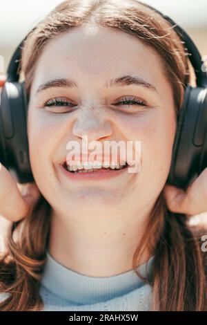Melodic Bliss: Primo piano Ritratto di una bella bruna perduta in Musical Delight, ritratto ravvicinato di una bella bruna che ascolta la musica con le cuffie e sorride il divertimento. Foto di alta qualità: Ecco la gioia e l'incanto di una splendida bruna che si immerge nella magia della musica, catturata in questo ritratto ravvicinato. Con le cuffie che adornano le orecchie, si immerge nella sinfonia melodica, con il suo volto che trasmette un sorriso autentico e puro piacere. I suoi occhi espressivi brillano di gioia, riflettendo le emozioni evocate dalla musica. Bellezza radiante e c Foto Stock