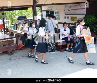 Studentesse mascherate che vanno a scuola alla stazione ferroviaria vicino a Bangkok, Thailandia Foto Stock