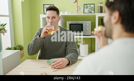 Due uomini sorridono fiduciosi di fare colazione nella sala da pranzo Foto Stock